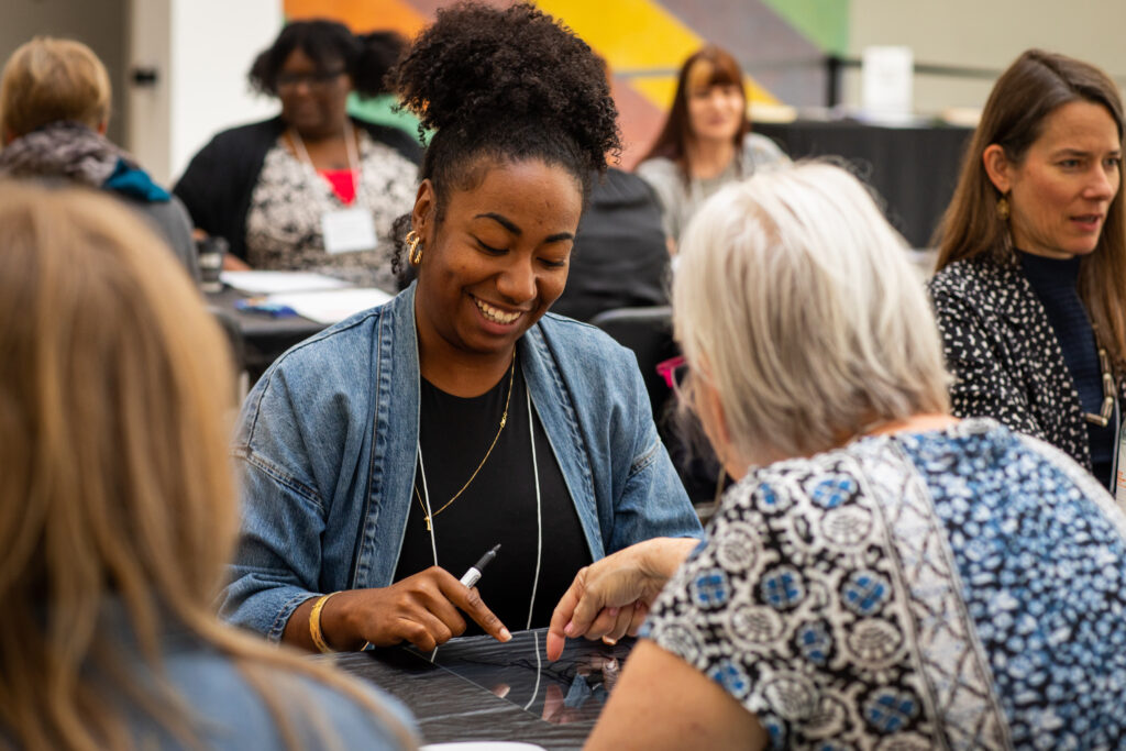 Convening on arts and aging 2023 139 A woman with brown skin smiles and looks down while drawing with a sharpie