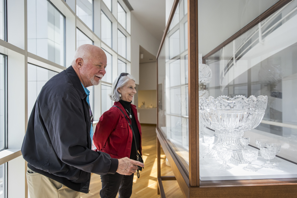 Two individuals looking at art in a display case.