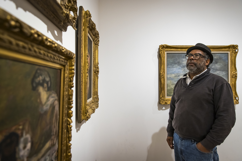 A man looks at European paintings in the Shaheen Collection