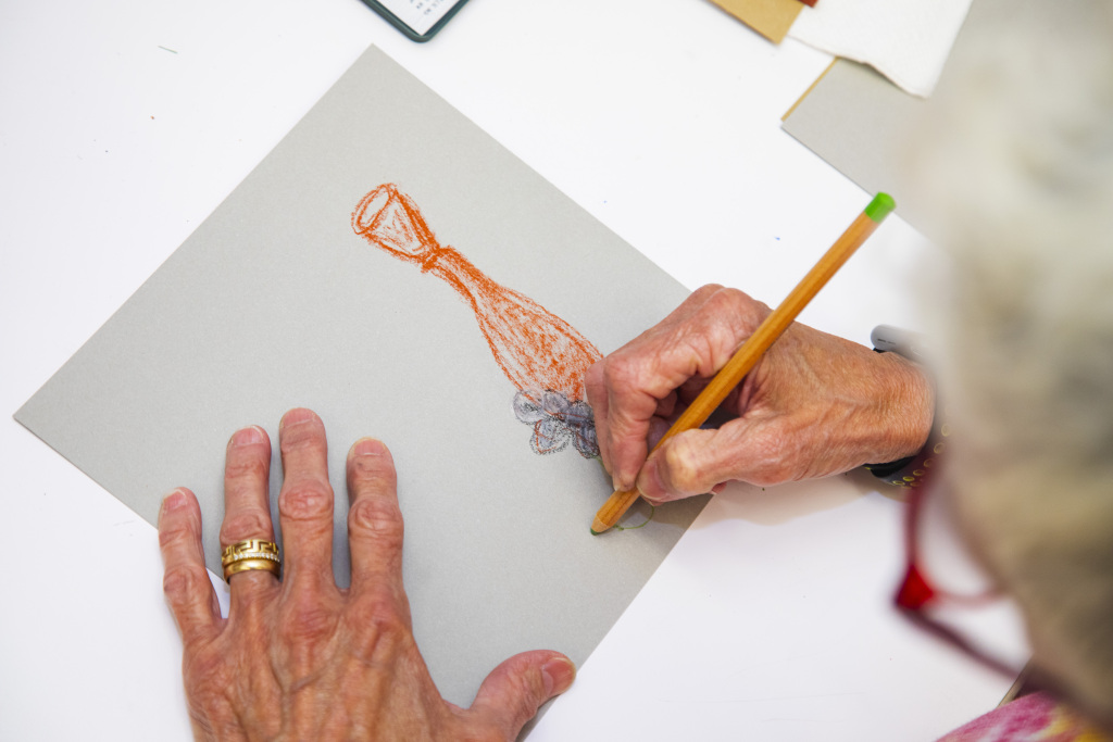 Highmuseum Classessampler2024 0062 O4 Overhead shot of person's hands drawing with an orange pencil.