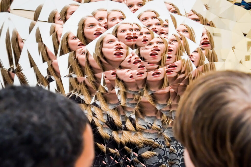 Steam Children's faces reflected over and over in a mirrored sculpture by Anish Kapoor.